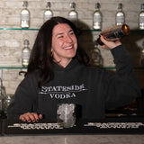 Person wearing a Stateside Vodka hoodie behind a bar with bottles of Stateside Vodka in the background