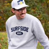 Person wearing a white "Surfside Est. 2021" hat and gray crewneck with "Surfside 2021" in an outdoor setting.