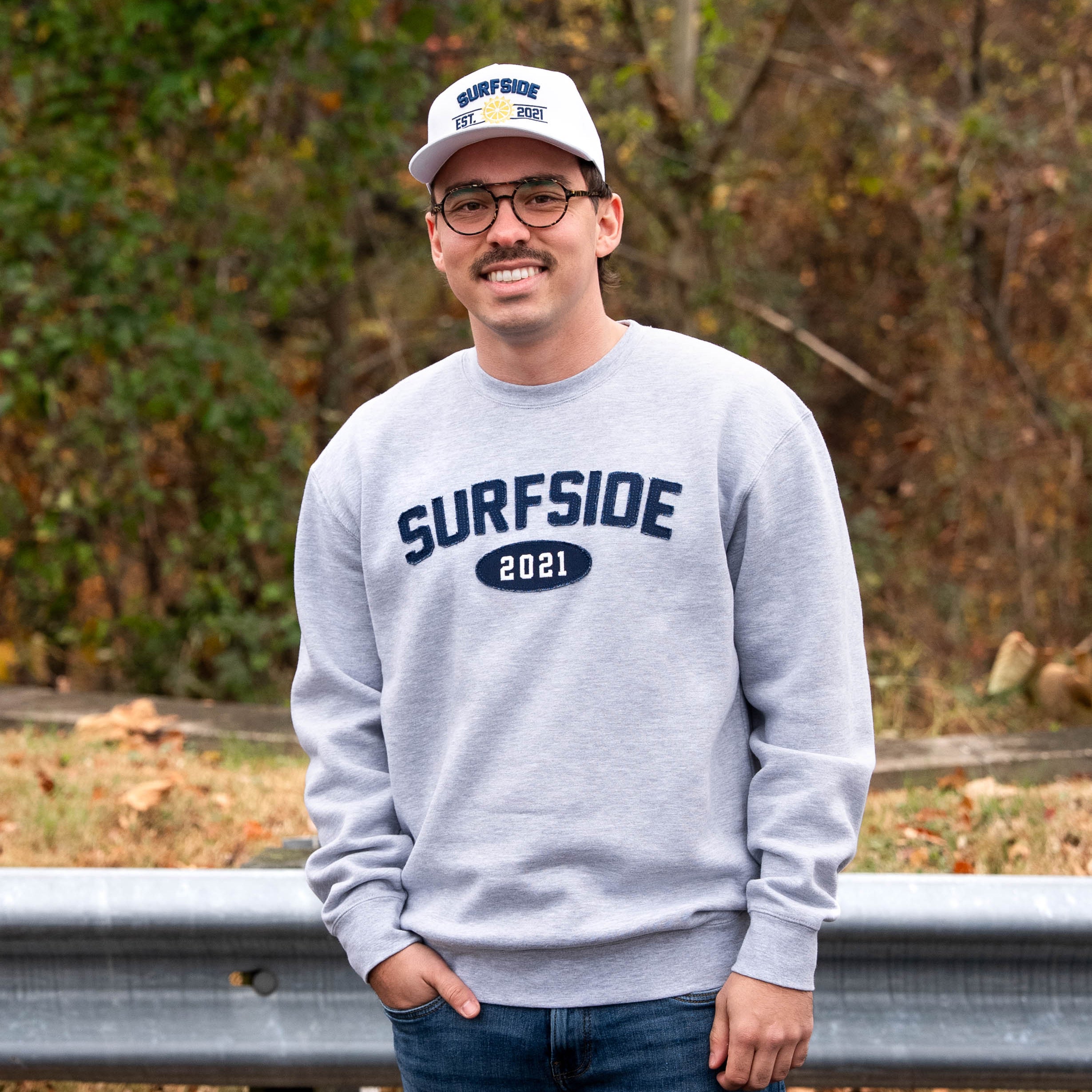Person wearing a grey 'Surfside 2021' crewneck and white 