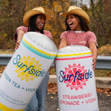 Two people holding two large inflatable shaped containers with Surfside branding outdoors.