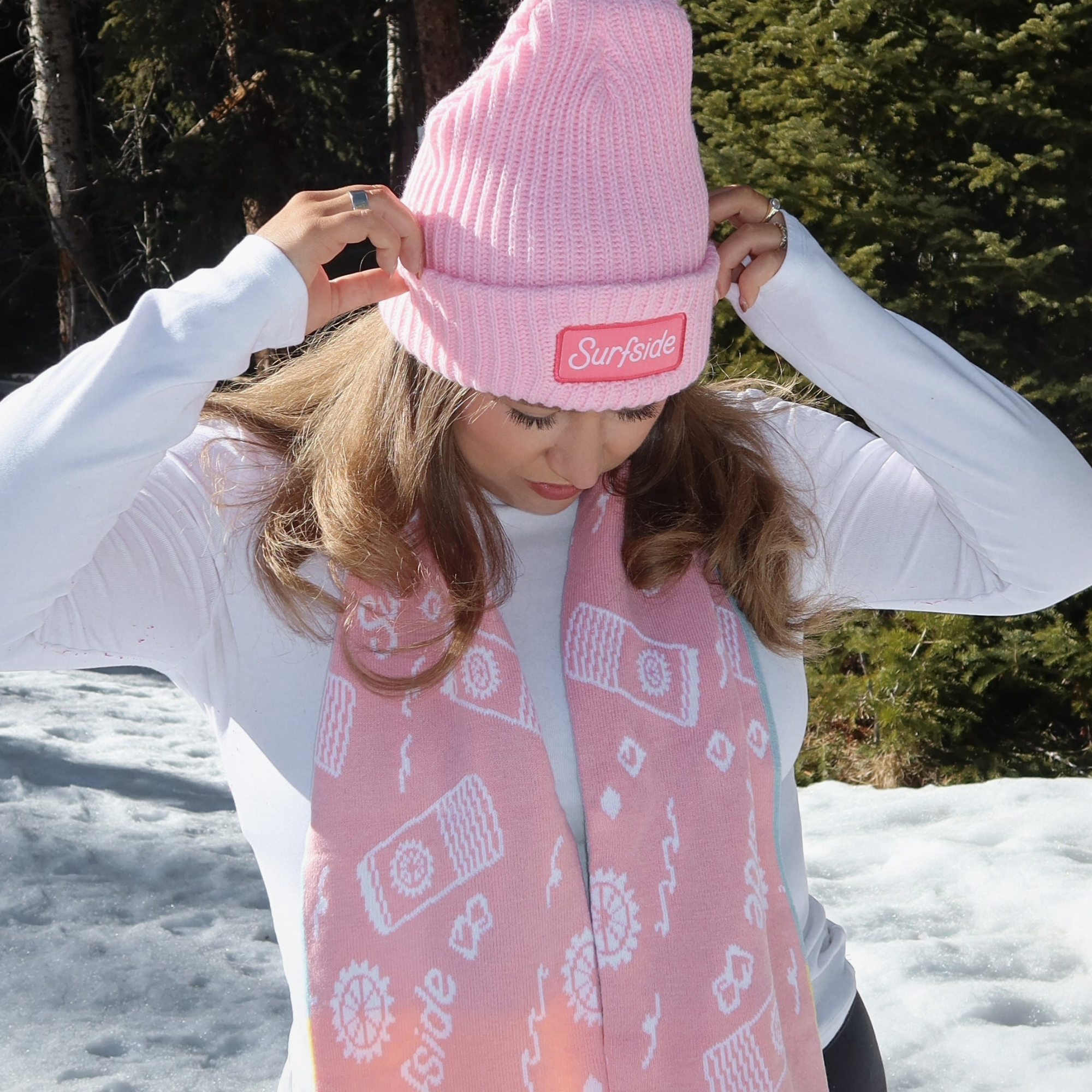 Person wearing a pink beanie and pink patterned Surfside scarf in a snowy background