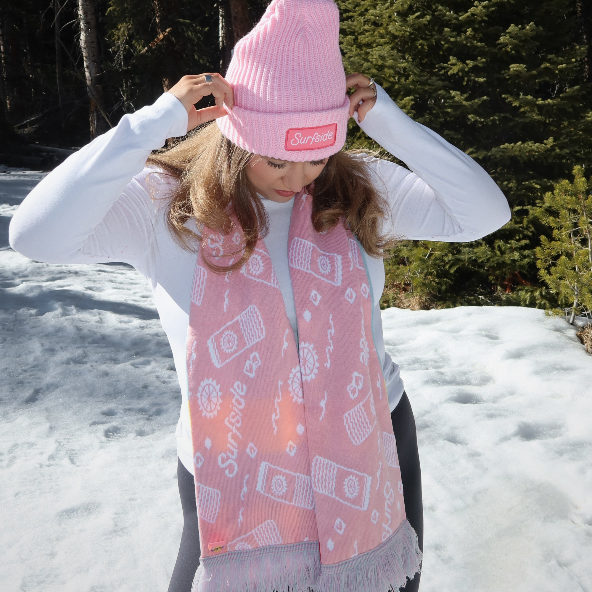 Person wearing a pink beanie and pink patterned Surfside scarf in a snowy 