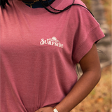 Person wearing a faded red 'Surfside' western inspired t-shirt with a blurred natural background