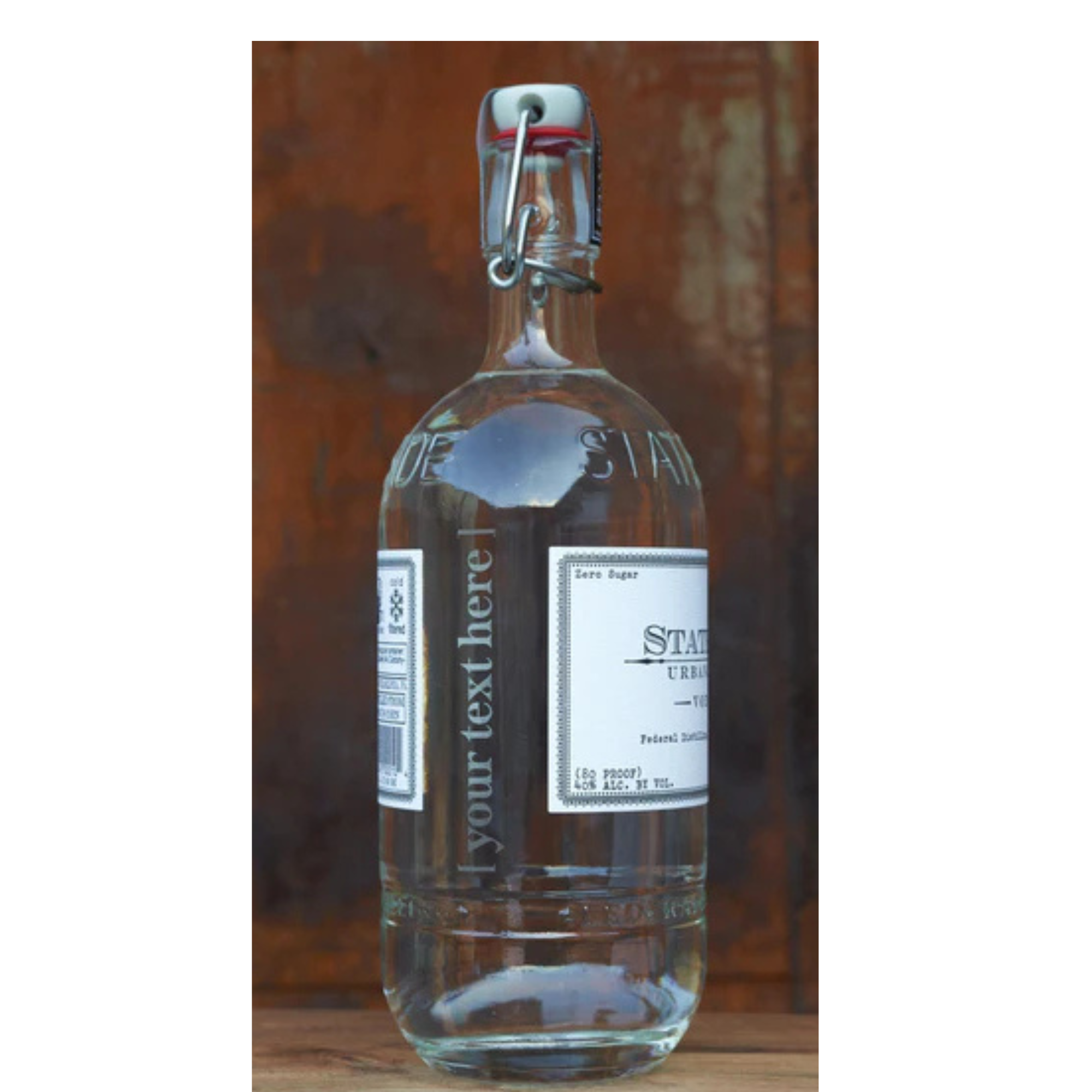 A clear glass bottle of Stateside vodka with a swing top lid, featuring a label and a custom laser-engraved design on the front.