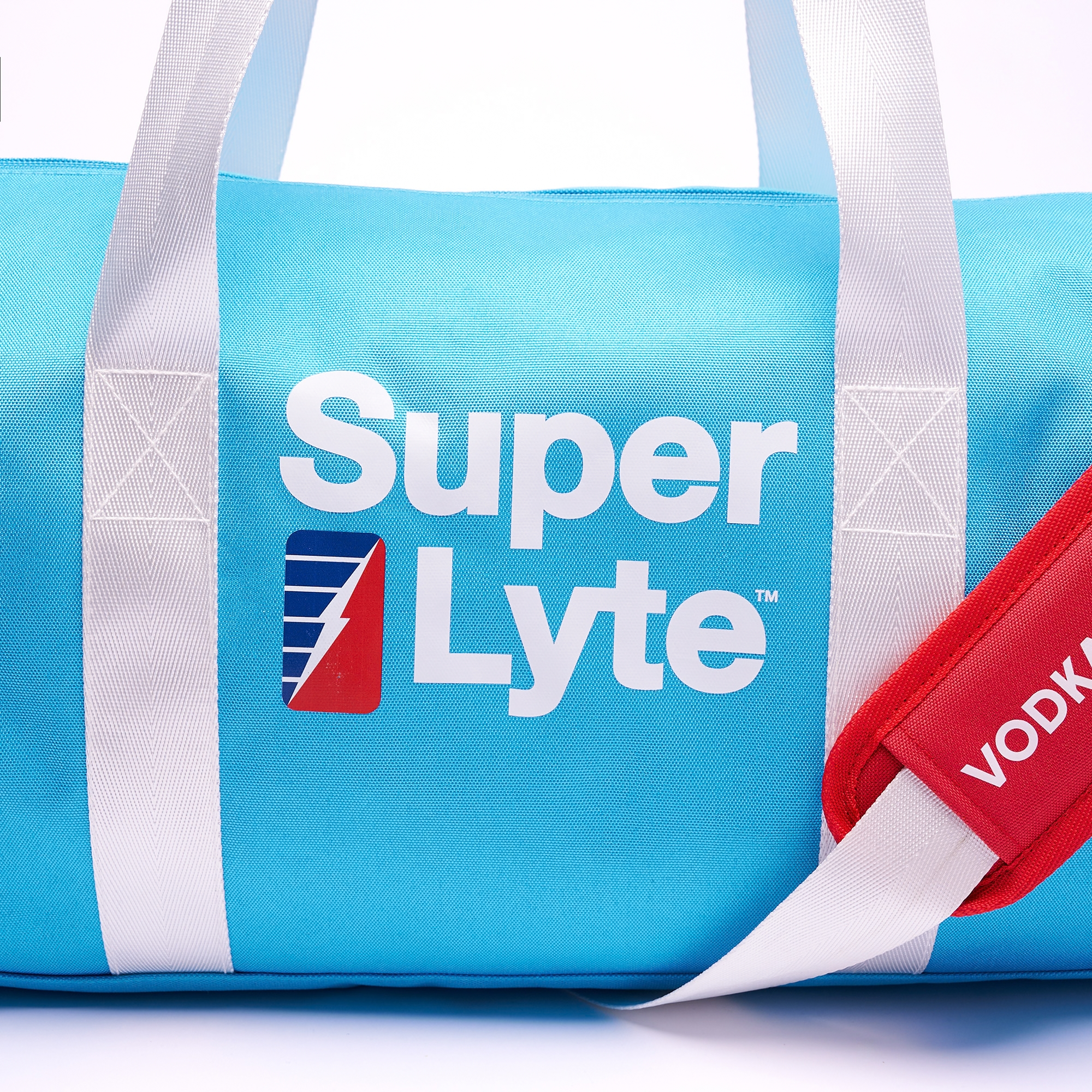 Close up of the Super Lyte Logo on the light blue Super Lyte duffel bag featuring white print and the Super Lyte bolt showing half of the red shoulder strap