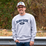 Person wearing a grey 'Surfside 2021' crewneck and white "Surfside Est. 2021" hat outdoors.