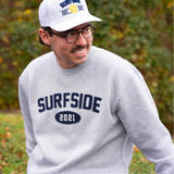 Person wearing a white "Surfside Est. 2021" hat and gray crewneck with "Surfside 2021" in an outdoor setting.