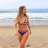 Woman in a colorful branded Surfside bikini standing on a beach with ocean waves in the background