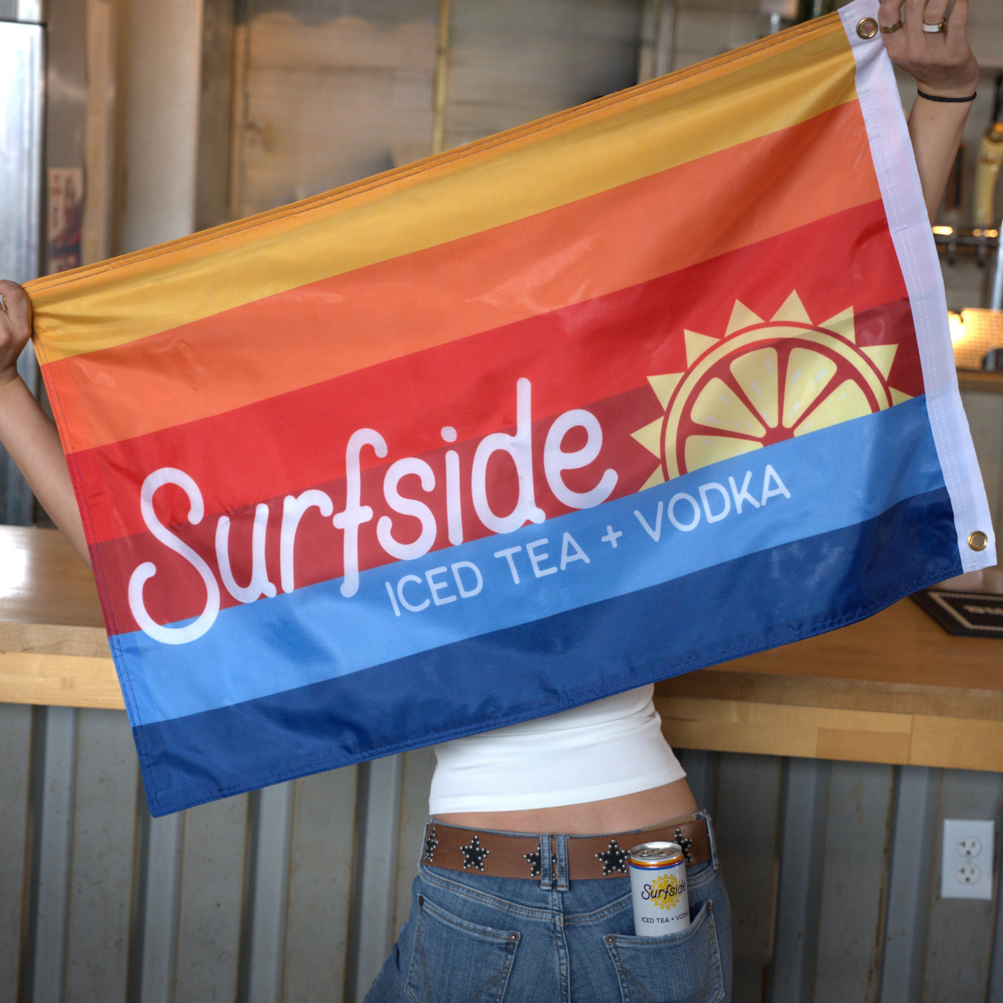 Person holding a colorful flag with 'Surfside' branding in an indoor setting.