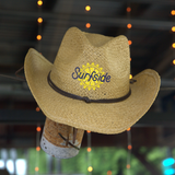 Straw cowboy hat with 'Surfside' logo with leather rope detailing around the brim on a blurred floating background