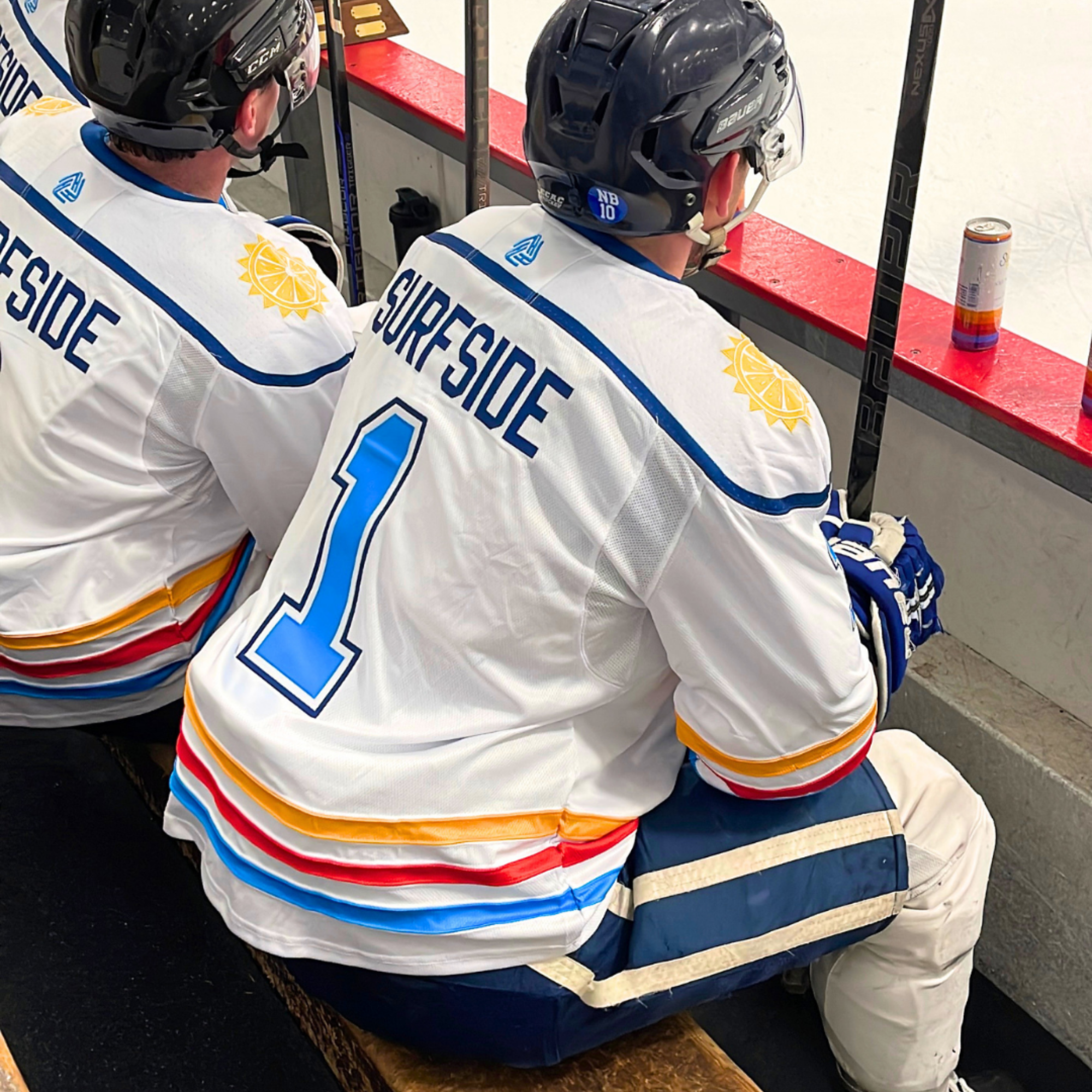 Two hockey players in 'Surfside' jerseys sitting on a bench.