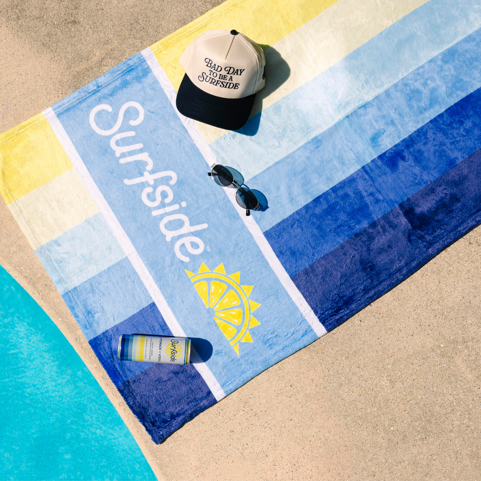 A beach towel laid on poolside with a cream cap reading 