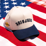 Beige and navy cap with an upside down 'Surfside' lettering. Featuring the Surfside logo on the side of the hat on an American flag 
