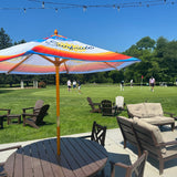 Surfside outdoor branded umbrella featuring in a table in an outdoor setting at a golf course with people playing golf in the background