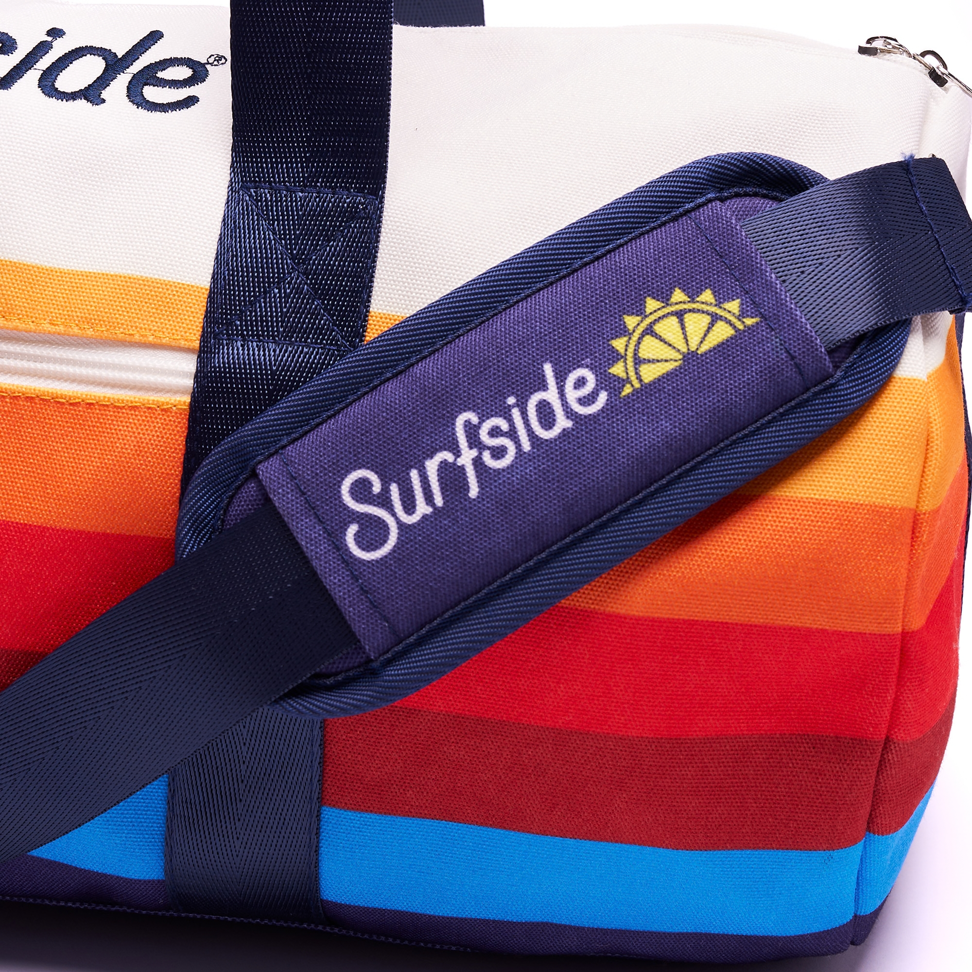 Close up of the Surfside duffel strap pad, featuring the Surfside logo and half a sun on a navy blue padding. Image also shows the brand color elements of the brand
