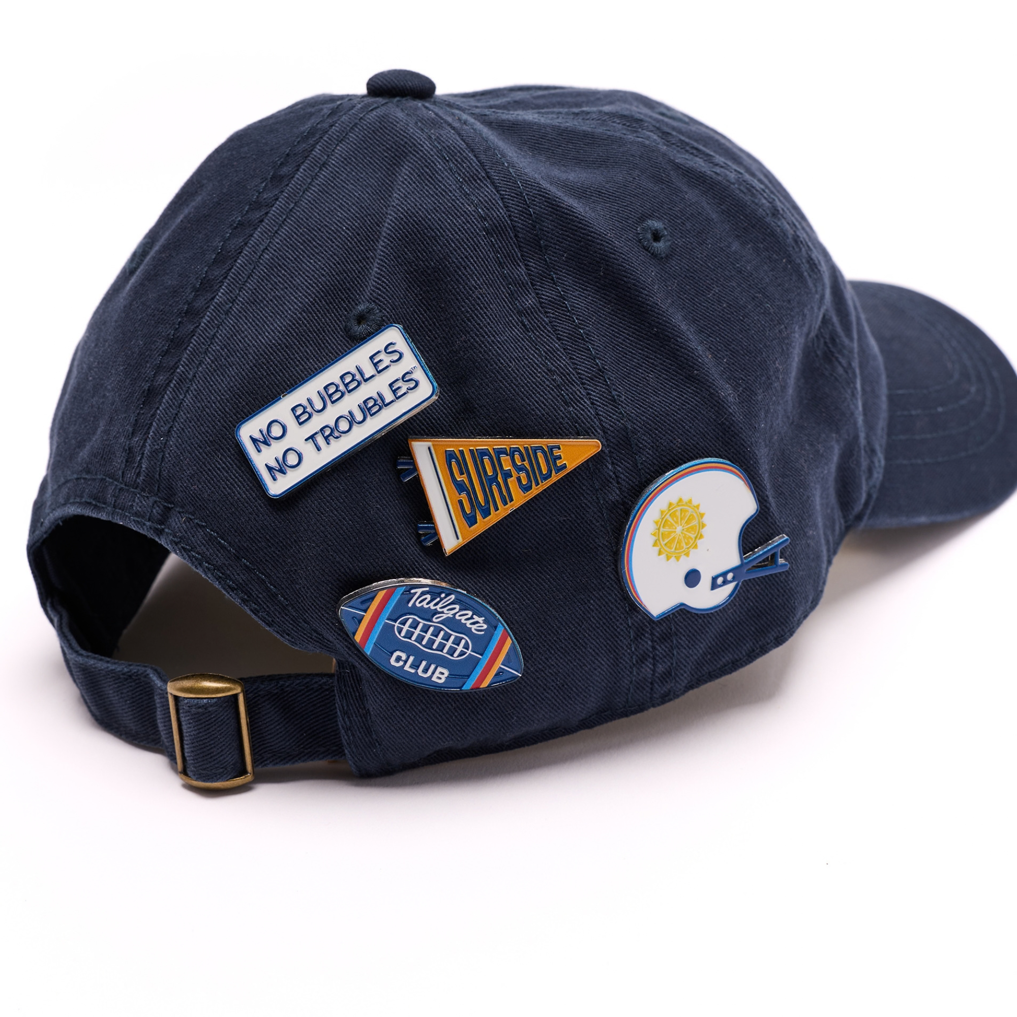 4 pins featured on a navy baseball hat. The pins are tailgate themed with Surfside brand elements