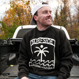 Man wearing a black sweatshirt with a logo saying "Surfside Watering Hole USA", sitting in the back of a pickup truck.