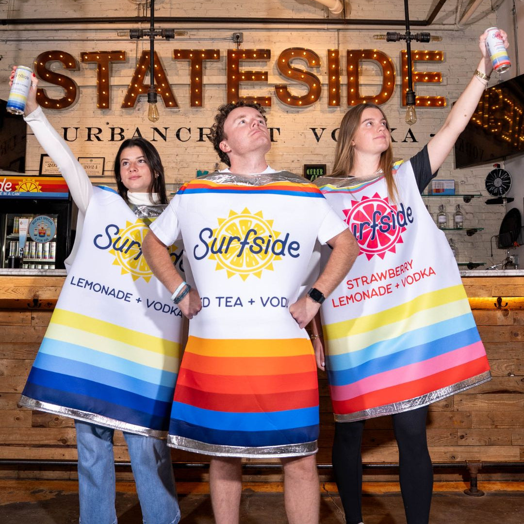 Three people wearing colorful Surfside can costumes in a bar setting.